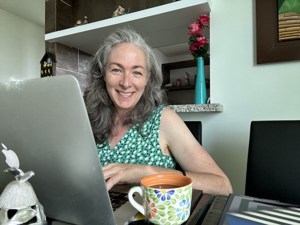 Picture of Dennise Cardona sitting in front of a laptop smiling.